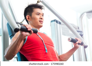 Asian Chinese Man Having Fitness Training Or Workout In Gym Doing Sport To Build Up Muscle On A Weight Machine