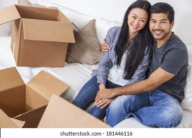 Asian Chinese Man And Woman Couple Packing Or Unpacking Boxes And Moving Into A New Home.