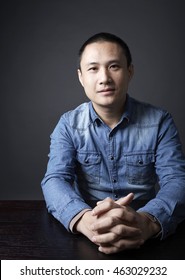 Asian Chinese man,confident,looking at camera, black background.

