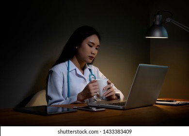 Asian Chinese Medical Doctor Personnel Like Sleeping With Coffee After A Night Shift Work Late At Night. Women Overwork Using Computer Laptop Reading E-mail At Doctor's Office.medical Health Concept