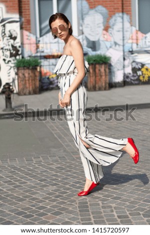 Asian Chinese model girl influencer street shot. Wearing striped white dress jumpsuit. Street Graffiti background.