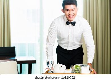 Asian Chinese Room Service Waiter Or Steward Serving Guests Food In A Grand Or Luxury Hotel Room 