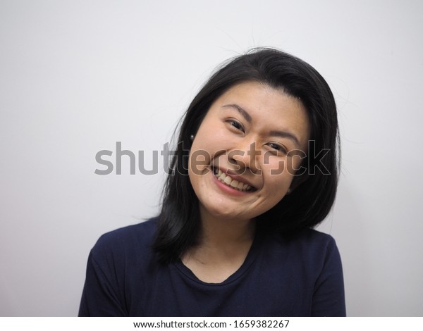 白い背景にアジア系の中国人の丸い顔の女性で 肩の長さの髪の毛が濃い青のtシャツでほほ笑みます の写真素材 今すぐ編集