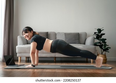 Asian Chubby Woman In Living Room Practice Online Yoga Lesson With The Computer. Female Having Meditate Training Class On The Laptop.