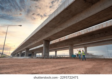 Asian civil engineers and foremen walking to inspect a road or expressway construction project under a road under construction.