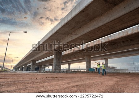 Asian civil engineers and foremen walking to inspect a road or expressway construction project under a road under construction.
