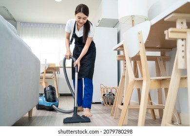 Asian Cleaning Service Woman Worker Cleaning In Living Room At Home. Beautiful Young Girl Housekeeper Cleaner Wear Apron And Vacuuming Messy Dirty Floor For Housekeeping Housework And Chores In House.