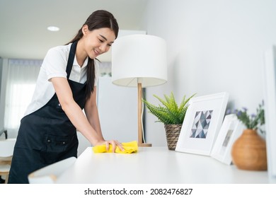 Asian Cleaning Service Woman Worker Cleaning In Living Room At Home. Beautiful Girl Housewife Housekeeper Cleaner Feel Happy And Wiping Messy Dirty Working Table For Housekeeping Housework Or Chores.