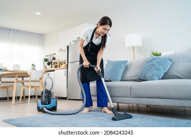 Asian Cleaning Service Woman Worker Cleaning In Living Room At Home. Beautiful Young Girl Housekeeper Cleaner Wear Apron And Vacuuming Messy Dirty Floor For Housekeeping Housework And Chores In House.