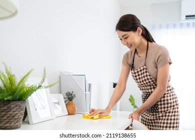 Asian Cleaning Service Woman Worker Cleaning In Living Room At Home. Beautiful Girl Housewife Housekeeper Cleaner Feel Happy And Wiping Messy Dirty Working Table For Housekeeping Housework Or Chores.