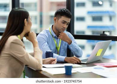 Asian colleagues man and woman discussing and working with laptop computer on office desk in the office - Shutterstock ID 1923745754
