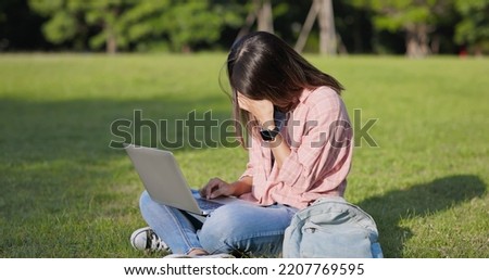 Asian college student feel frustrated with laptop on legs in a park 