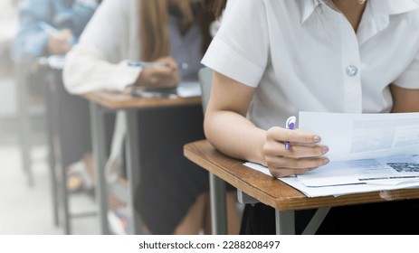 Los estudiantes universitarios asiáticos se concentran en hacer exámenes en el aula. Fotografía del stock educativo