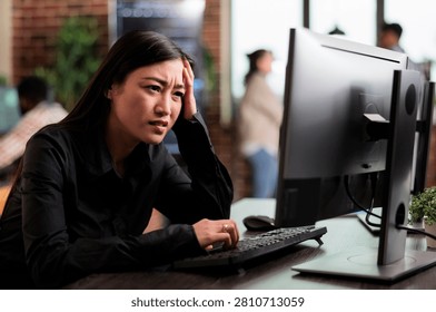 Asian computer engineer looks puzzled by a nonfunctional security algorithm, suggesting troubleshooting and problem solving during coding work.