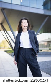 Asian Confident Business Woman In Suit Smiling, Looking Up To Bright Future Of Her Career Opportunities. Job, Work Aspirational Banner, Spring Background Of Office Center. Business People Lifestyle