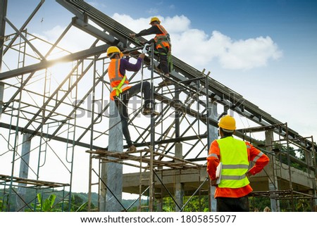 Asian construction worker control in the construction of roof structures and worker wear safety height equipment to install the roof. Fall arrestor device for worker with hooks for safety body harness