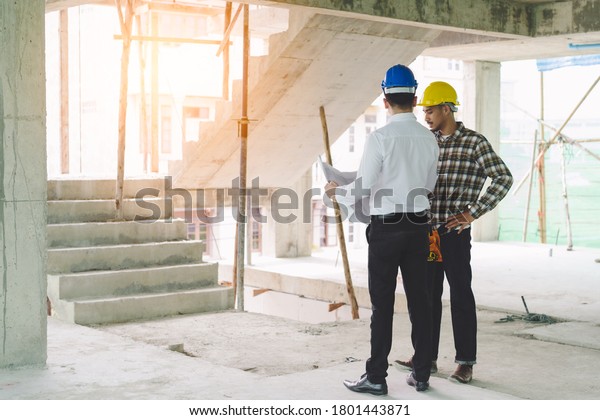 Asian contractor and engineer inspecting\
material in construction\
building.