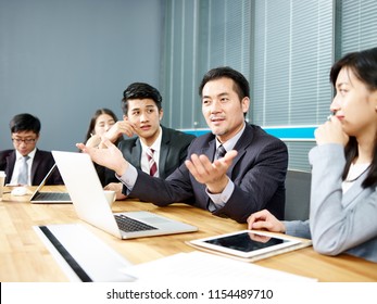 Asian Corporate Executive And His Business Team Meeting And Negotiating With Client.