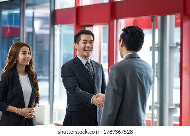 asian corporate executives shaking hands with visiting client in elevator hall of modern office building - Powered by Shutterstock