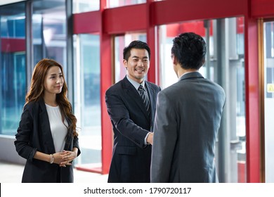 asian corporate executives shaking hands with visiting client in elevator hall of modern office building - Powered by Shutterstock