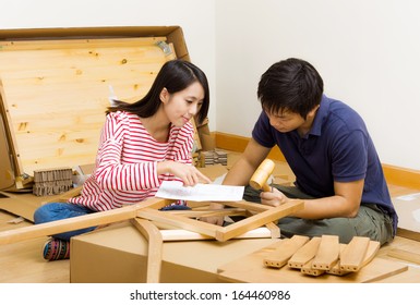 Asian Couple Assembling New Furniture