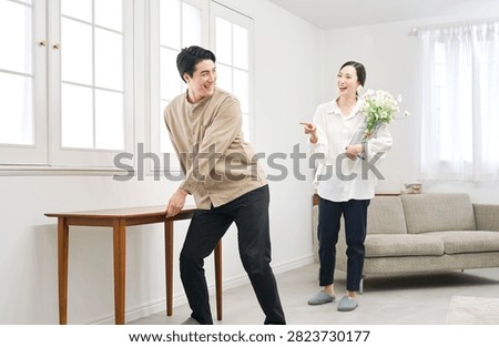 Asian couple carrying table while rearranging living room