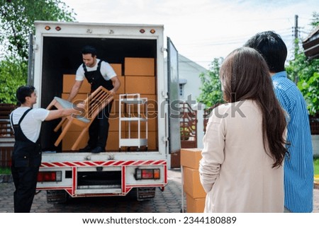 Asian Couple check while unloading boxes and furniture from a pickup truck to a new house with service cargo two men movers worker in uniform lifting boxes. concept of Home moving and delivery.