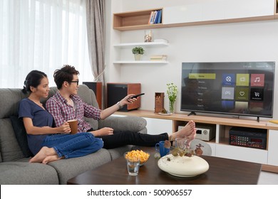 Asian couple choosing channel on their smart tv