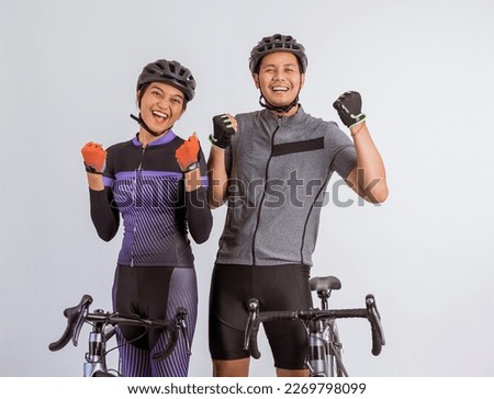 asian couple in cycling outfit standing with clenched arms while standing beside their bicycles on isolated background