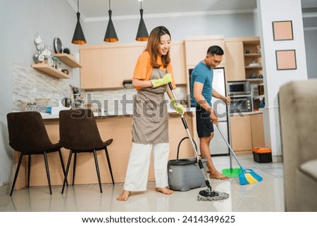 asian couple doing household chores together by mopping and sweeping the floor