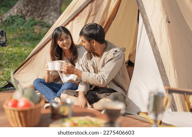 Asian couple drinking coffee enjoying camping outdoors in nature. Man traveler hands holding cup of coffee. - Powered by Shutterstock