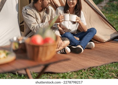 Asian couple drinking coffee enjoying camping outdoors in nature. Man traveler hands holding cup of coffee. - Powered by Shutterstock