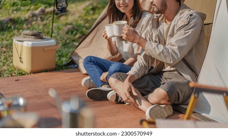 Asian couple drinking coffee enjoying camping outdoors in nature. Man traveler hands holding cup of coffee. - Powered by Shutterstock