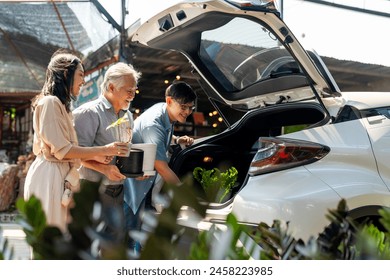 Asian couple with elderly father put potted plants and flower in car trunk together after buying plant at street market on summer vacation. Family relationship and senior people mental health care. - Powered by Shutterstock