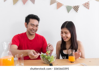 Asian couple feeding each other with salad, lover lifestyle concept.