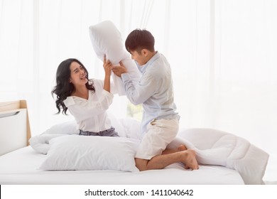 Asian couple flirting on bed together They have fun playing with pillow fight in bedroom. - Powered by Shutterstock