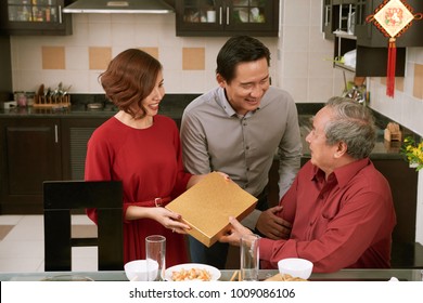 Asian couple giving present for Tet to grandfather