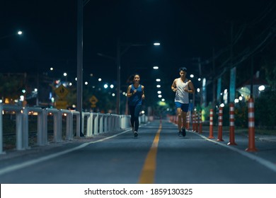 Asian Couple Jogging In The City Streets At Night