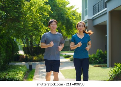 Asian couple are jogging in the neighborhood for daily health and well being, both physical and mental and simple antidote to daily stresses and to socialize safely.