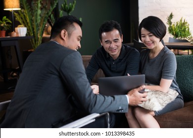 Asian Couple Listening To A Presentation By A Financial Advisor.