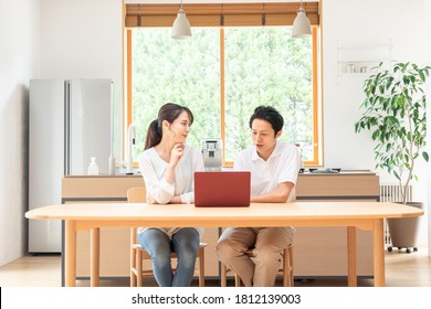 Asian Couple Looking At A Computer In The Living Room