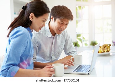 Asian Couple Looking At Laptop In Kitchen