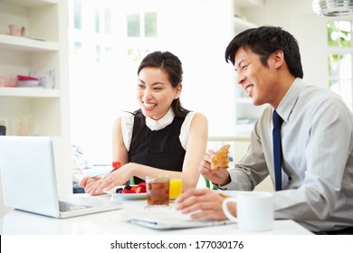 Asian Couple Looking At Laptop Over Breakfast