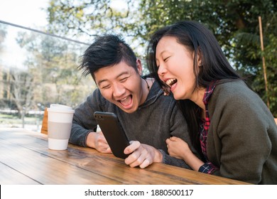 Asian Couple Looking At The Mobile Phone.