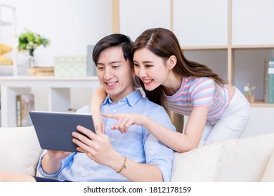 Asian Couple Looking Some Information On The Internet Together By Digital Tablet At Home Happily