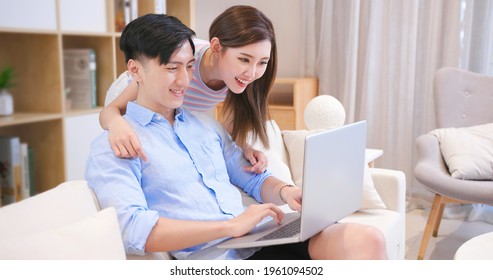 asian couple looking some information on the internet together with laptop computer at home happily
