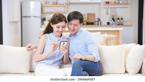 asian couple looking some information on the internet together with smart phone at home happily