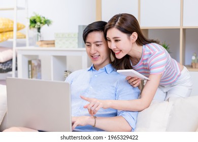 Asian Couple Looking Some Information On The Internet By Laptop Together At Home Happily