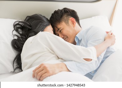Asian Couple Lying In Bed Together, They Hug Each Other With Love.