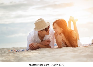 Asian Couple Lying Honeymoon At Sunset Tropical Beach In Thailand